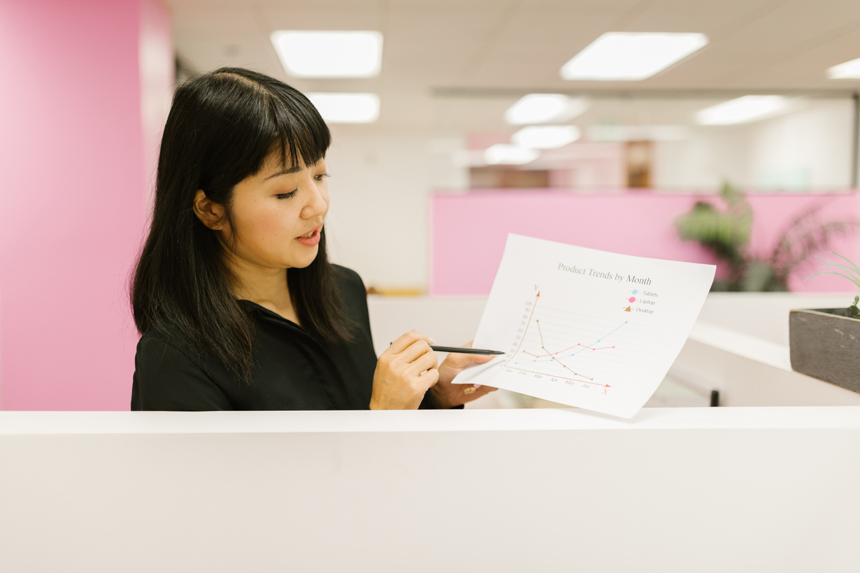 A Woman in the Office Holding a Document with with Graphs